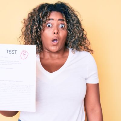 Young african american plus size woman showing a failed exam scared and amazed with open mouth for surprise, disbelief face